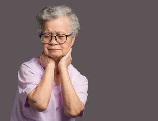 Senior woman suffering from neck pain standing on a gray background