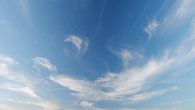 Floating fluffy cirrus clouds. Beautiful sunny blue sky with wispy smoky white. Timelapse.