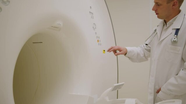 A male doctor approaches the MRI machine before the examination. Setting up expensive equipment before the study in the clinic