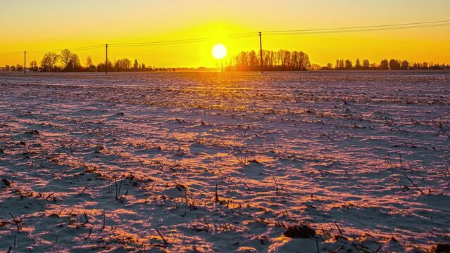 Timelapse, a landscape of frozen farm soil in winter with morning sun rising