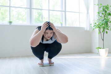 体重計に乗って頭を抱える女性
