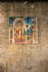 old painted print of buddha on decayed wall in asia