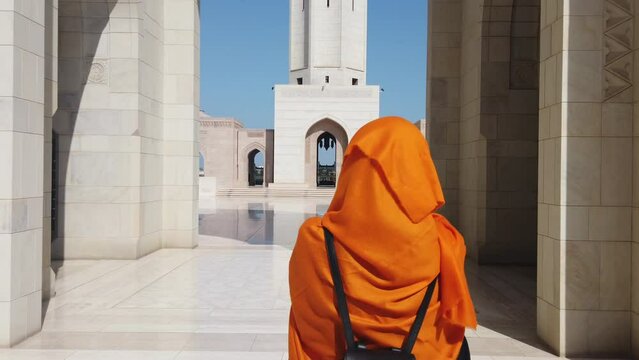 woman walking with orange hijab in mosque