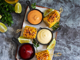 grilled yellow head corn with spices lime close up white red orange sauce portion - 549942932
