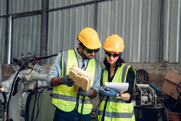 Team of Engineers is controlling robot arm machine welding steel, worker using forcing welding with a control screen which is used for precision welding control.