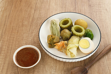 Siomay Bandung (Shumay) or steamed dumplings with boiled egg, tofu, potatoes and cabbage roll. Indonesian traditional street food with peanut sauce and soy sauce, and green lime.
