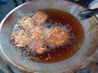 Frying bakwan in a skillet with boiling hot oil, delicious crispy savory taste. Traditional Indonesian snacks. At the Car free day event.