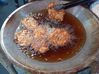 Frying bakwan in a skillet with boiling hot oil, delicious crispy savory taste. Traditional Indonesian snacks. At the Car free day event.