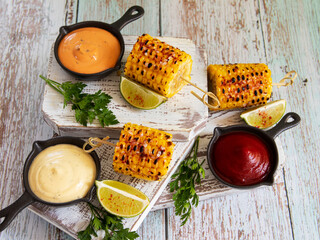 grilled yellow head corn with spices lime close up white red orange sauce portion - 549946150