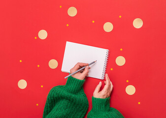 woman in a green sweater on a red background holds a notepad in her hands, a space for copying