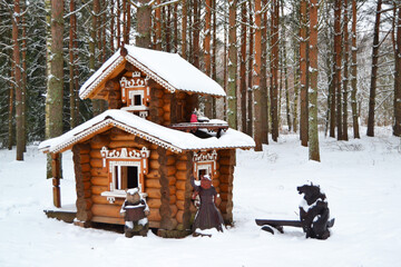 Wooden beautiful carved fairy tale house in the winter forest around the snow