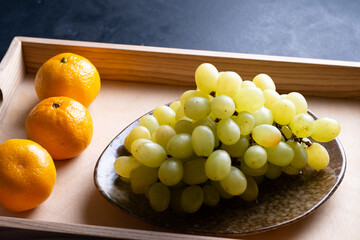 Wooden tray with grape on plate, tangerines.