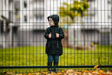 An orphan is standing in orphanage on the rain left alone.