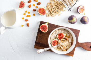 delicious healthy breakfast of oatmeal with fruit, oatmeal freshly cooked in a bowl on a cutting board. top view. white background.