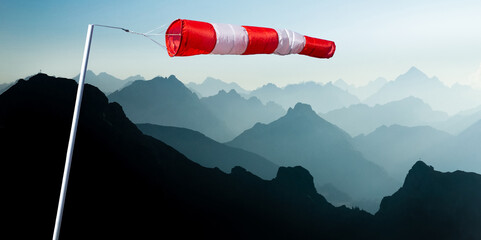 Striped Windbag and Mountain Silhouettes at Sunrise. Concept for creative business ideas. Alps, Allgau, Bavaria, Germany. - 549948706
