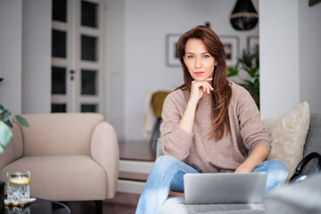 Smiling caucasian woman using her laptop and working at home