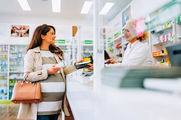 Pregnant woman buying medication with cellphone.