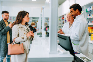 Naklejka premium Pregnant woman talking to pharmacists at drugstore.