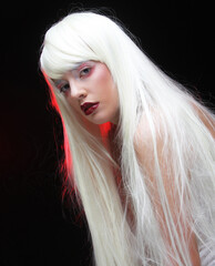 Beautiful young woman with long white hair over dark background with smole.