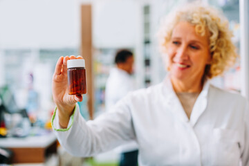 Caucasian pharmacist holding bottle of medicine.