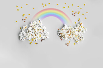 
creative food concept layout with clouds made of popcorn, drawn rainbow and confetti stars. flat lay cinema style. copy space. top view