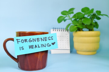 Forgiveness is healing motivation and inspiration message concept. Selective focus of a cup of coffee with handwritten bright paper note.