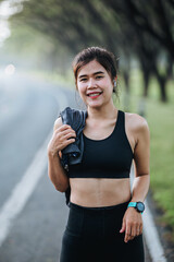 Young asian women drink water and stand to rest after jogging a morning workout in the city. A city that lives healthy in the capital. Exercise, fitness, jogging, running, lifestyle, healthy concept.