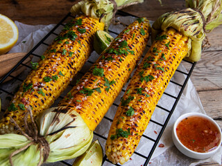 three heads of yellow corn grilled lemon lime spicy, white orange red sauce, rustic style