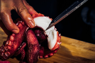 Close up of Chef cook hands chopping octopus for traditional Asian cuisine with Japanese knife....