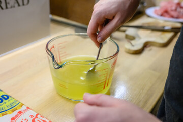 hands stirring stock in a measuring jug