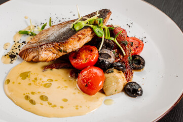 Tasty grilled dorada fish with boiled vegetables and sauce on wooden background