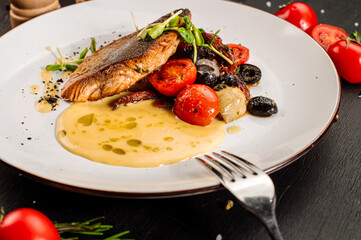 Tasty grilled dorada fish with boiled vegetables and sauce on wooden background