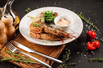 Dish of big king shrimps with herbs on wooden background