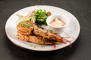 Dish of big king shrimps with herbs on wooden background