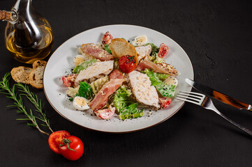 Tasty fresh salad ceasar with ham and vegetables on black background