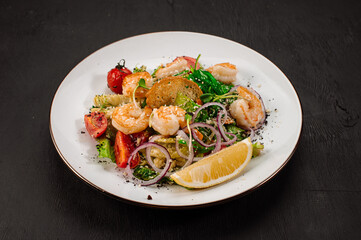 Tasty salad with shrimps, herbs and vegetables on black background