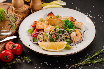 Tasty salad with shrimps, herbs and vegetables on black background