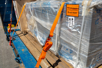 Tension safety belts with mechanical locks. On a pallet or in a container box, the cargo is held by tension safety belts with mechanical locks and ratchet Straps. - obrazy, fototapety, plakaty