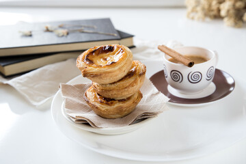 Pasteis de nata, traditional sweet of Portuguese cuisine. Small crunchy puff pastry pies and a cream made with eggs. Often tasted and accompanied with coffee. Set table, on white background.