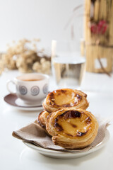 Pasteis de nata, traditional sweet of Portuguese cuisine. Small crunchy puff pastry pies and a cream made with eggs. Often tasted and accompanied with coffee. Breakfast table set.