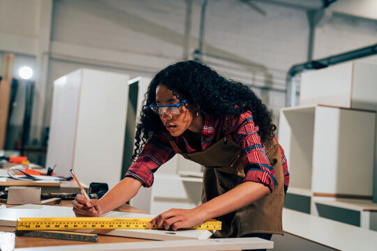Young woman working as carpenter in a small carpentry workshop, Small family business concept of young entrepreneurs