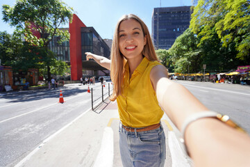 Fototapeta premium Travel in Sao Paulo, Brazil. Beautiful smiling girl takes self portrait on Paulista Avenue, Sao Paulo, Brazil.