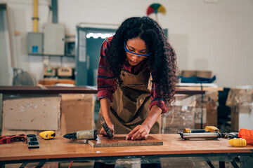 Young woman working as carpenter in a small carpentry workshop, Small family business concept of young entrepreneurs - obrazy, fototapety, plakaty