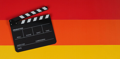 Clapper board or movie slate on yellow red and orange background.