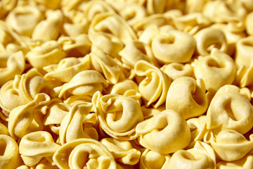 Tortellini pasta with prosciutto food background. Italian stuffed pasta