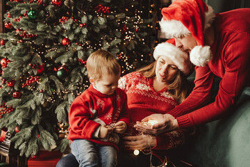 Happy family under Christmas tree. baby boy in Santa Claus hat with gifts under Christmas tree with...