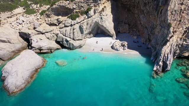 Aerial drone video of famous pebble paradise beach of Seychelles, popular for turquoise azure waters and natural volcanic cave formations, Ikaria island, Northeast Aegean, Greece