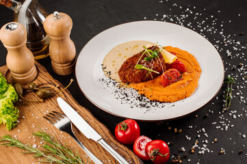 Dish of tasty cuttlet with puree and vegetables on wooden background