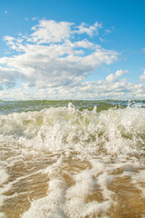Close-up of an approaching sea wave. Positive joyful background on the theme of a fun beach holiday, vacation and travel. Healthy marine recreation. Bright sunny day on a warm seashore.