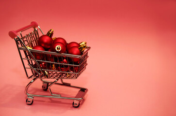 shopping cart trolley filled with christmas red balls decorations and big copy space like graphic christmas shopping and cost and price of festive time concept 